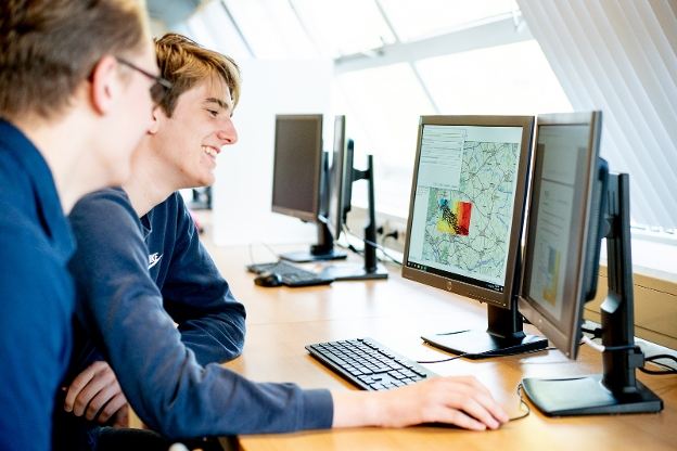 Studenten werken achter computer aan landkaart